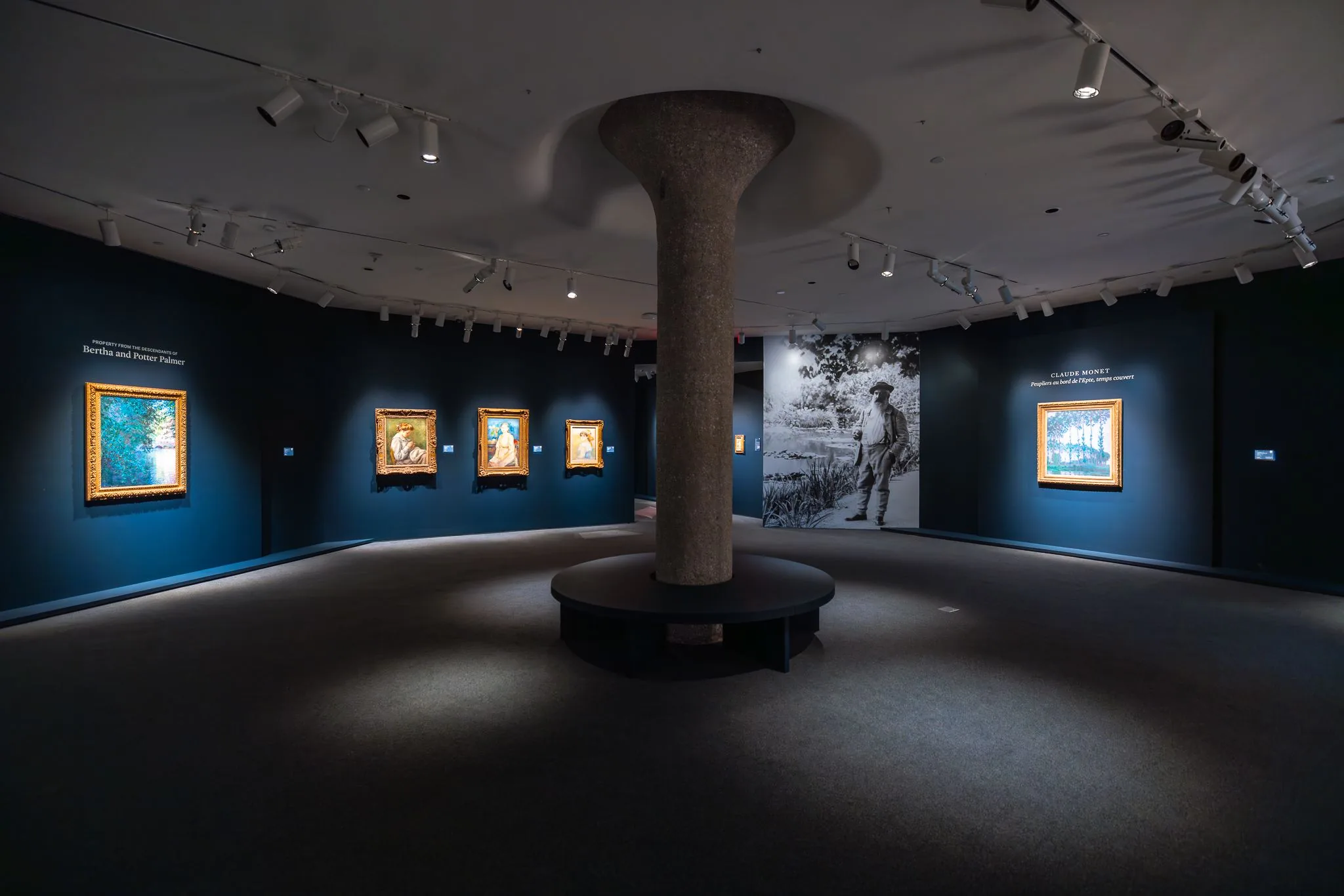 Pinturas y retratos en una galería con paredes azules